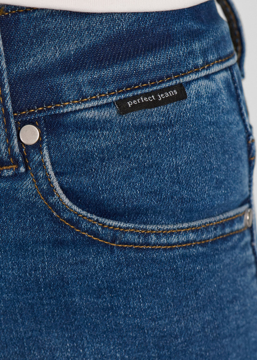 Nærbillede af mørkeblå denim med Perfect Jeans logoetiket ved forlommekanten.