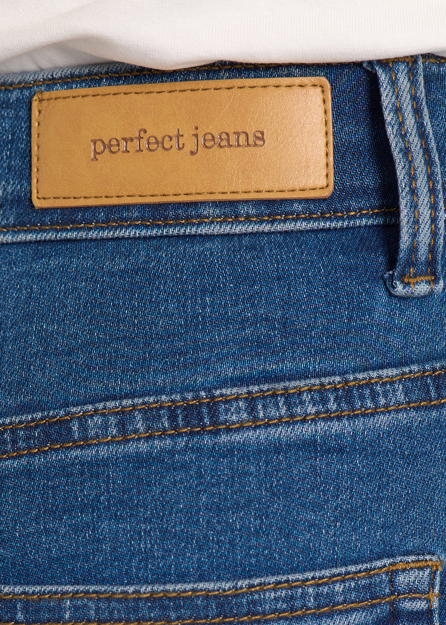 Nærbillede af mørkeblå denim med Perfect Jeans læderpatch bagpå i taljen.