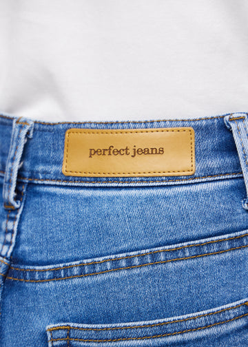Close-up of blue denim with the Perfect Jeans leather patch at the back of the waistband.