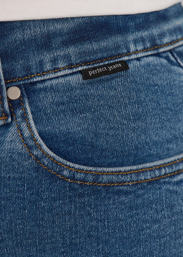 Nærbillede af mørkeblå denim med Perfect Jeans logoetiket ved forlommekanten, på en plus-size model.