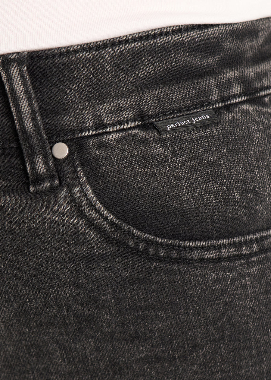 Nærbillede af mørkegrå denim med Perfect Jeans logoetiket ved forlommekanten, på en plus-size model.
