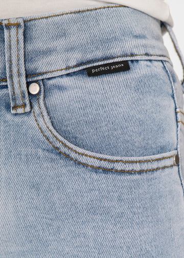 Nærbillede af lyseblå denim med Perfect Jeans logoetiket ved forlommekanten.
