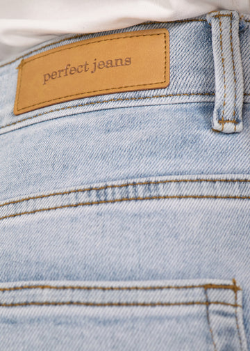 Nærbillede af lyseblå denim med Perfect Jeans læderpatch bagpå i taljen.