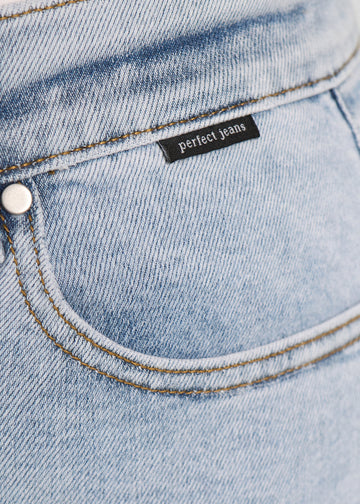 Nærbillede af lyseblå denim med Perfect Jeans logoetiket ved forlommekanten, på en plus-size model.