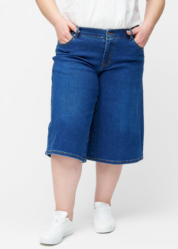Løse, mørkeblå denim capris i farven Oceans set forfra på plus-size model, der sidder til ved hoften og falder løst ned.