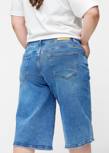 Løse, klassisk blå denim capris i farven Rivers set bagfra tæt på på plus-size model for at vise pasform og detaljer.