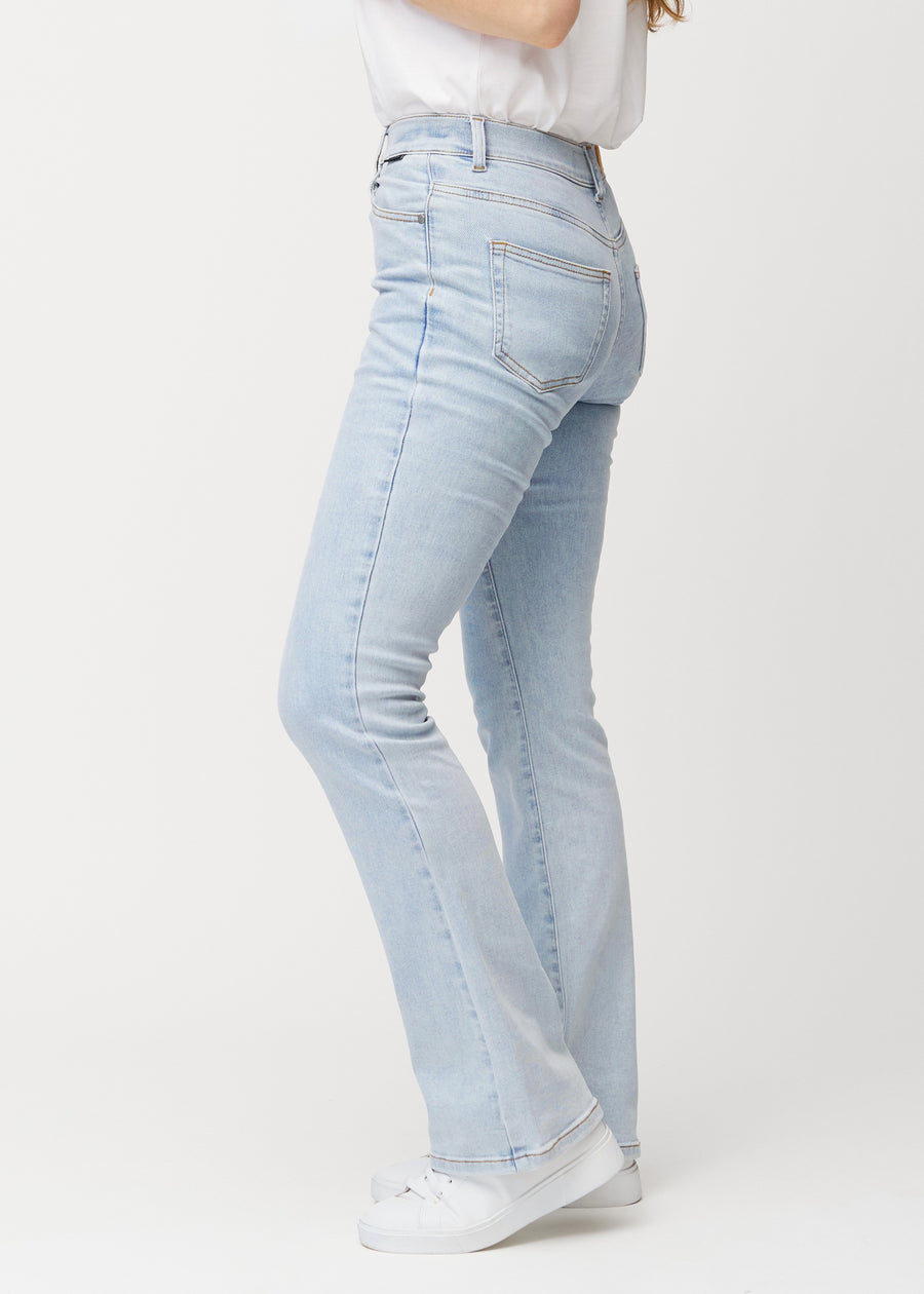 Light blue mid-rise bootcut jeans in Waves. Side view on a model.