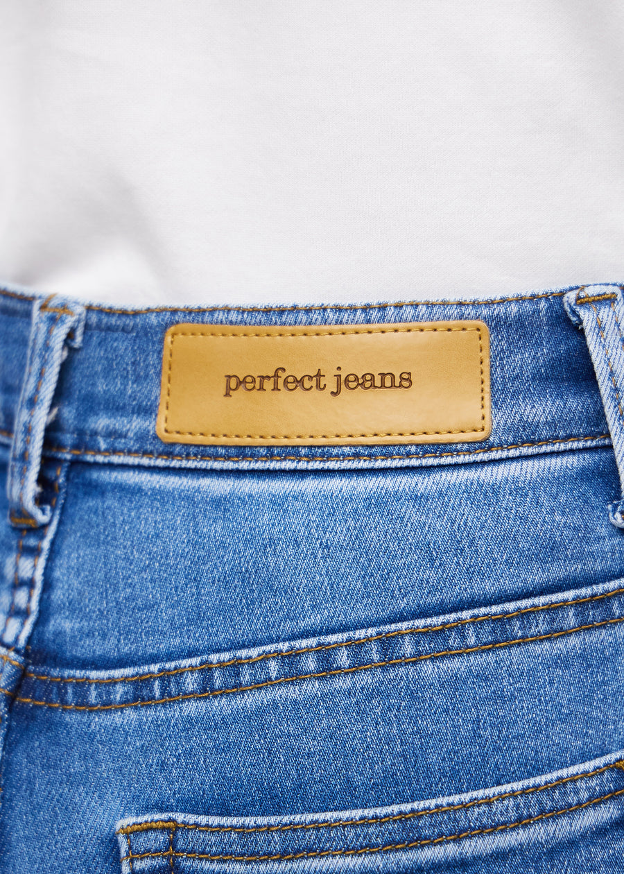 Nærbillede af blå denim med Perfect Jeans læderpatch bagpå i taljen.