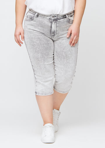 Light grey denim regular capris, model name Ashes, which have a straight fit through the leg and end just below the knee on a plus-size model, seen from the front.
