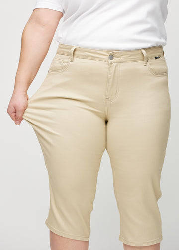 Plus-size model stretches the capris at the thigh to show the stretch.