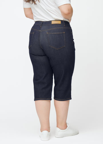 Deep dark blue denim capris for women in the colour Midnights seen from the back on a plus-size model.
