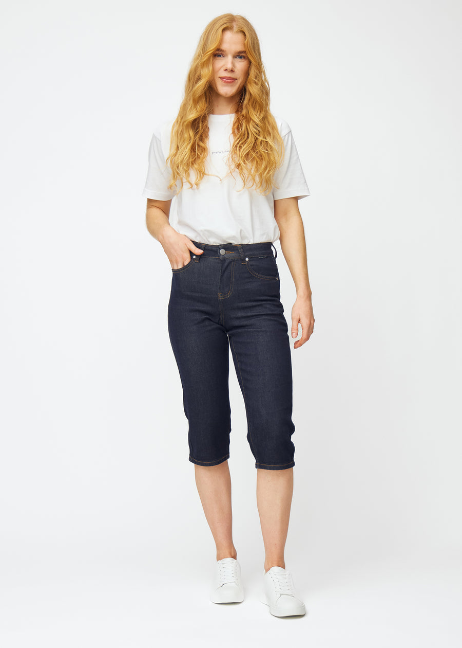 Full image of a model wearing deep dark blue denim capris for women in the colour Midnights with a regular fit.
