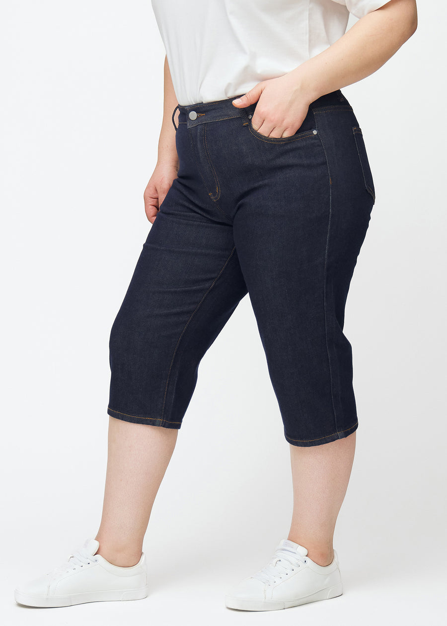 Deep dark blue denim capris for women in the colour Midnights with a regular fit seen from the side on a plus-size model.
