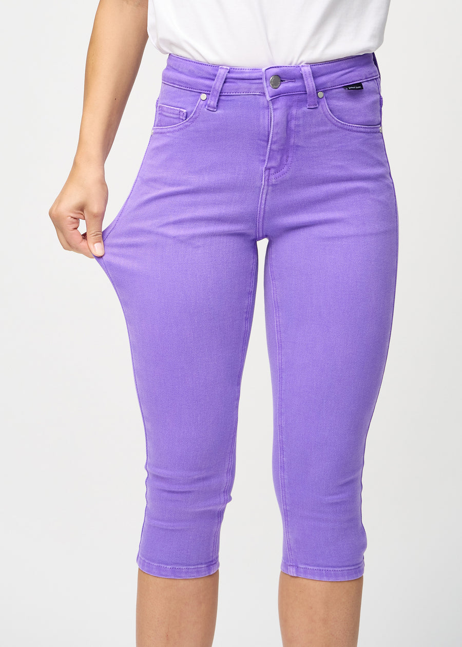Skinny capris for women in pastel purple fabric, color Lavenders. A model stretches the fabric to demonstrate its flexibility.