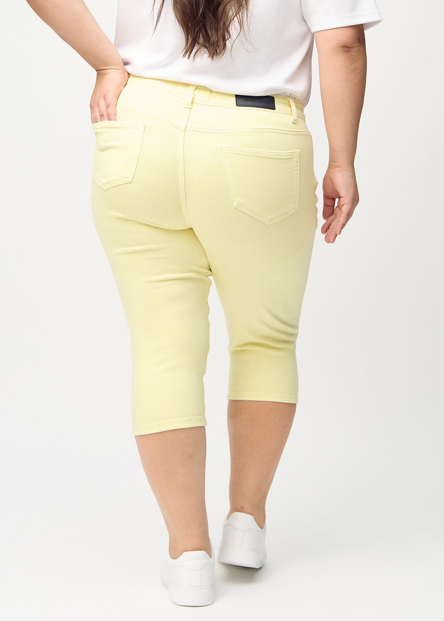 Skinny capris for women in pastel yellow fabric, color Lemonades. Back view on a plus-size model, showing the fit and back pockets.