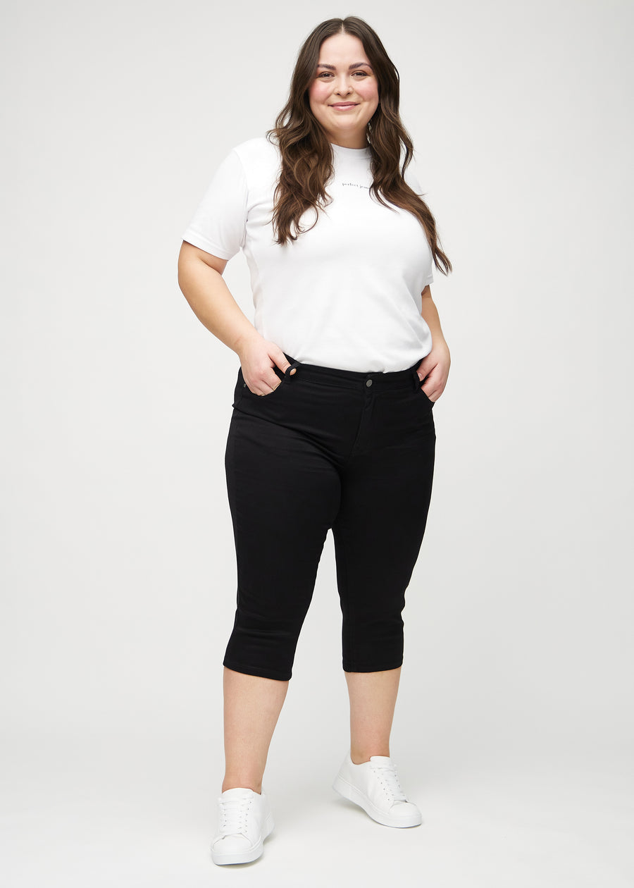 Skinny capris for women in black fabric, color Ravens. Full-length view of a plus-size model wearing the capris.