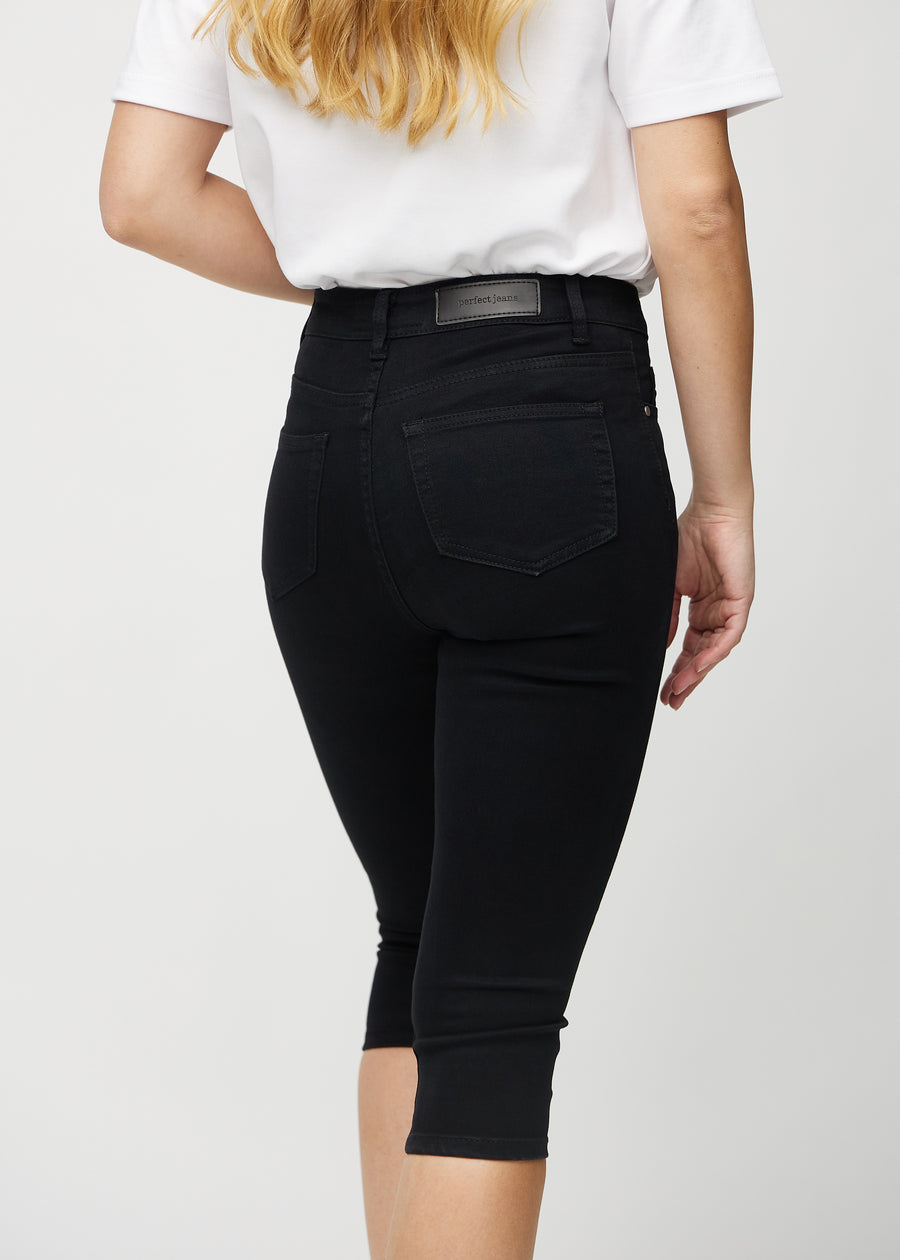 Skinny capris for women in black fabric, color Ravens. Close-up from behind on a model, highlighting pockets and stitching.