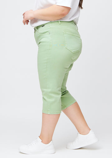 Slim capris for women in pastel light green jeans fabric, color Mints. Side view on a plus-size model, showing the tailored fit and mid-rise waist.