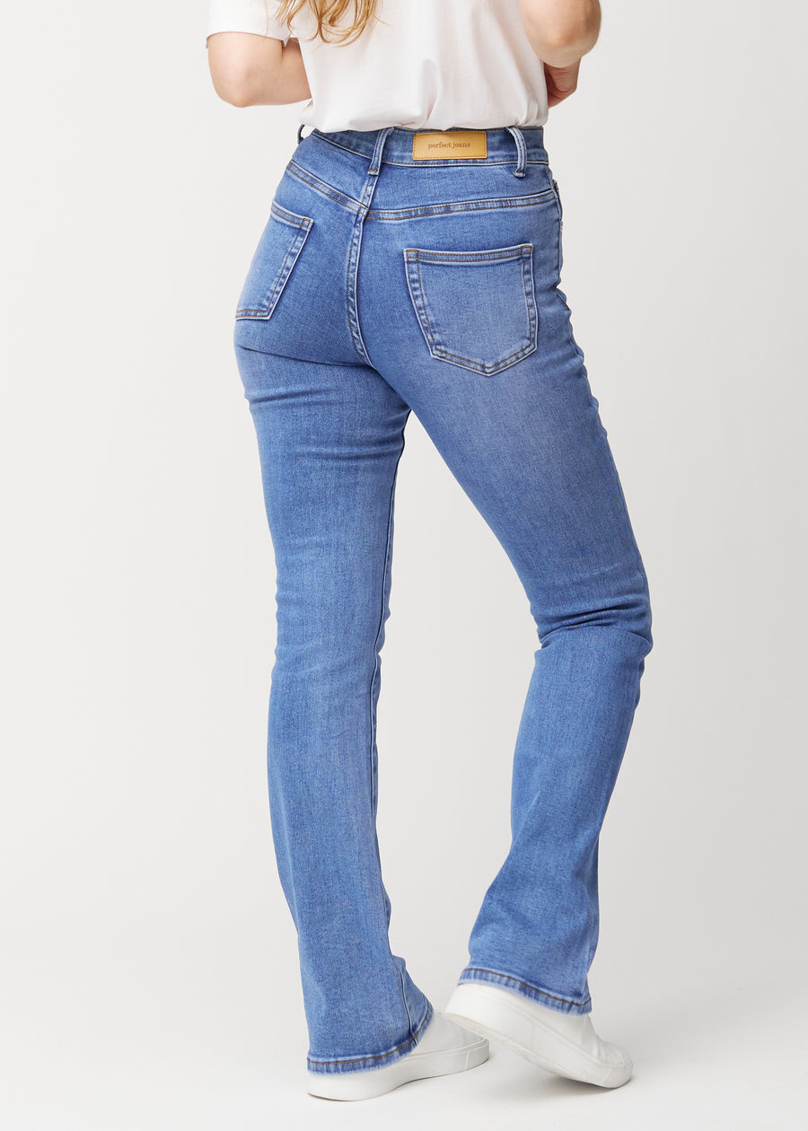 Blue mid-rise bootcut jeans in Rivers. Back view on a model, showing the full fit.