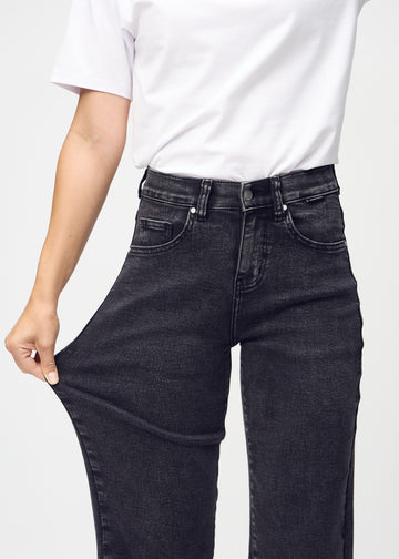Loose jeans for women in dark grey, color Shadows. A model stretches the denim at the thigh to show the fabric&