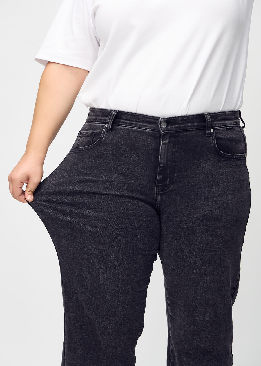 Loose jeans for women in dark grey, color Shadows. A plus-size model stretches the denim at the thigh to show the fabric&