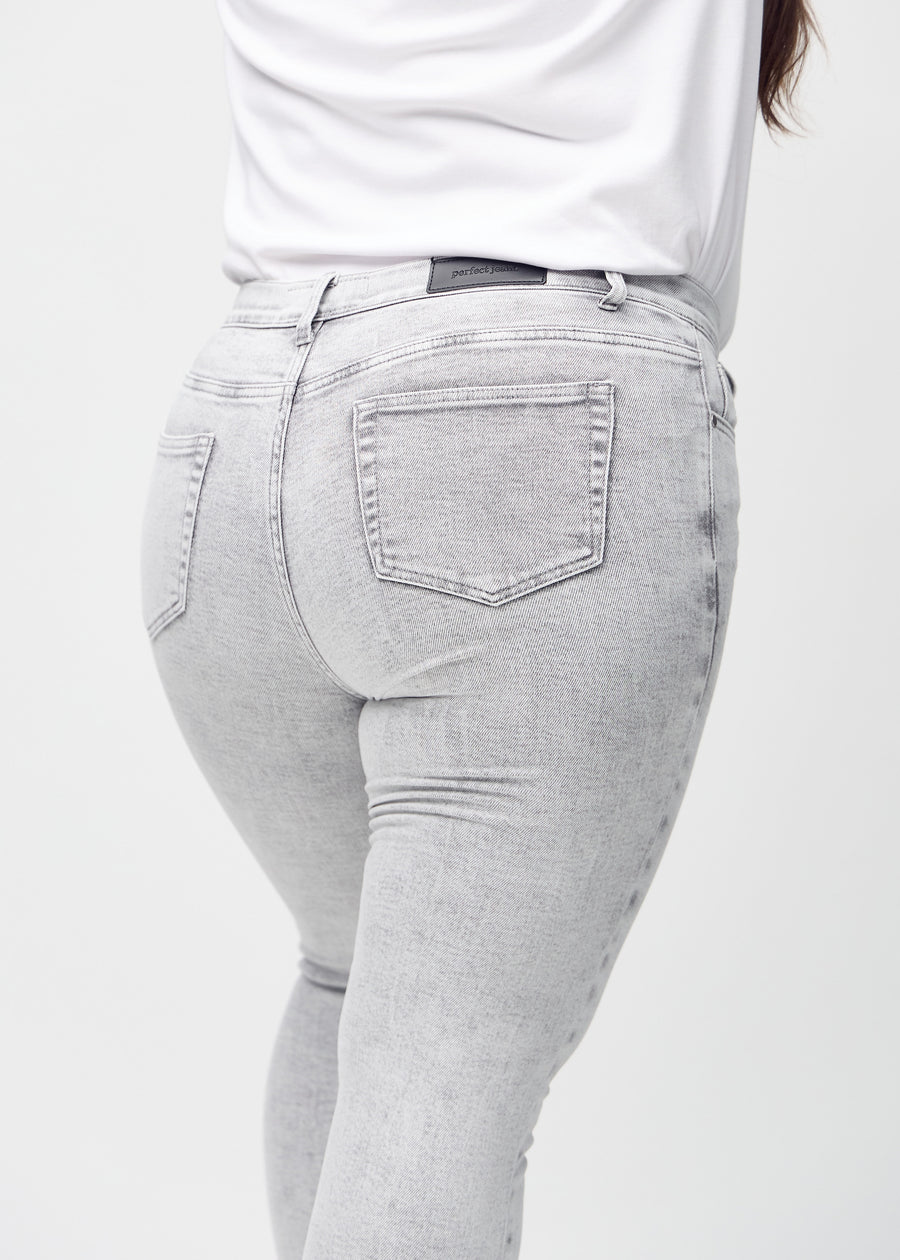 Skinny jeans for women in light grey, color Ashes. Close-up back view on a plus-size model, showing details.