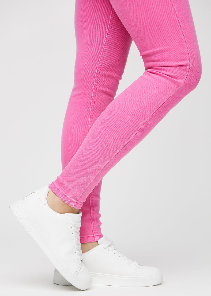 Skinny jeans for women in light pink, color Flamingos. Close-up of the snug-fitting leg openings at the ankles on a model.