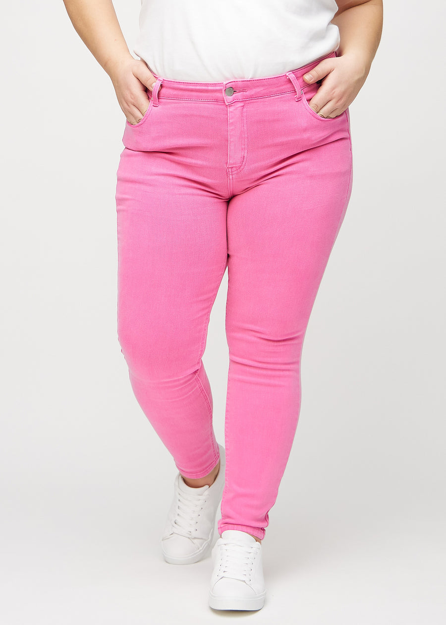 Skinny jeans for women in light pink, color Flamingos. Front view on a plus-size model, showing the close fit through the legs.
