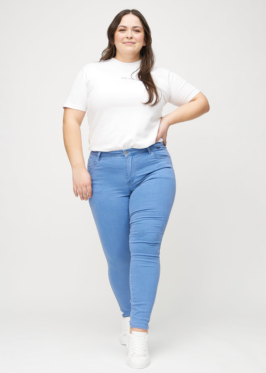 Full image of a plus-size model in blue skinny jeans.