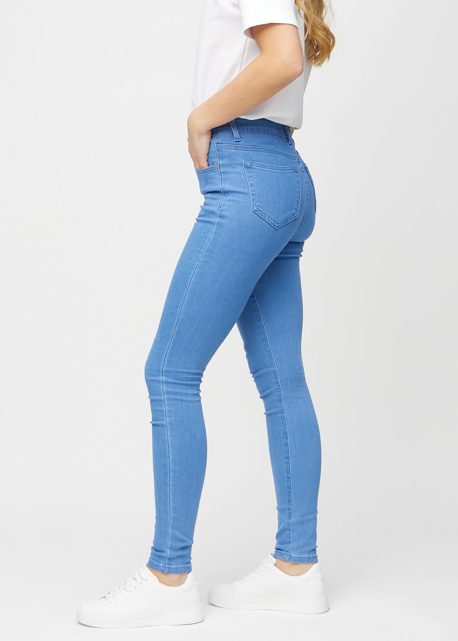 Blue skinny jeans seen from the side on a model.