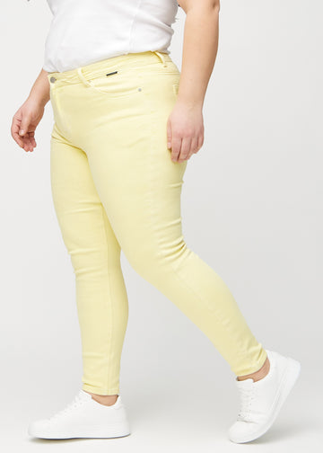 Skinny jeans for women in light yellow, color Lemonades. Side view on a plus-size model.