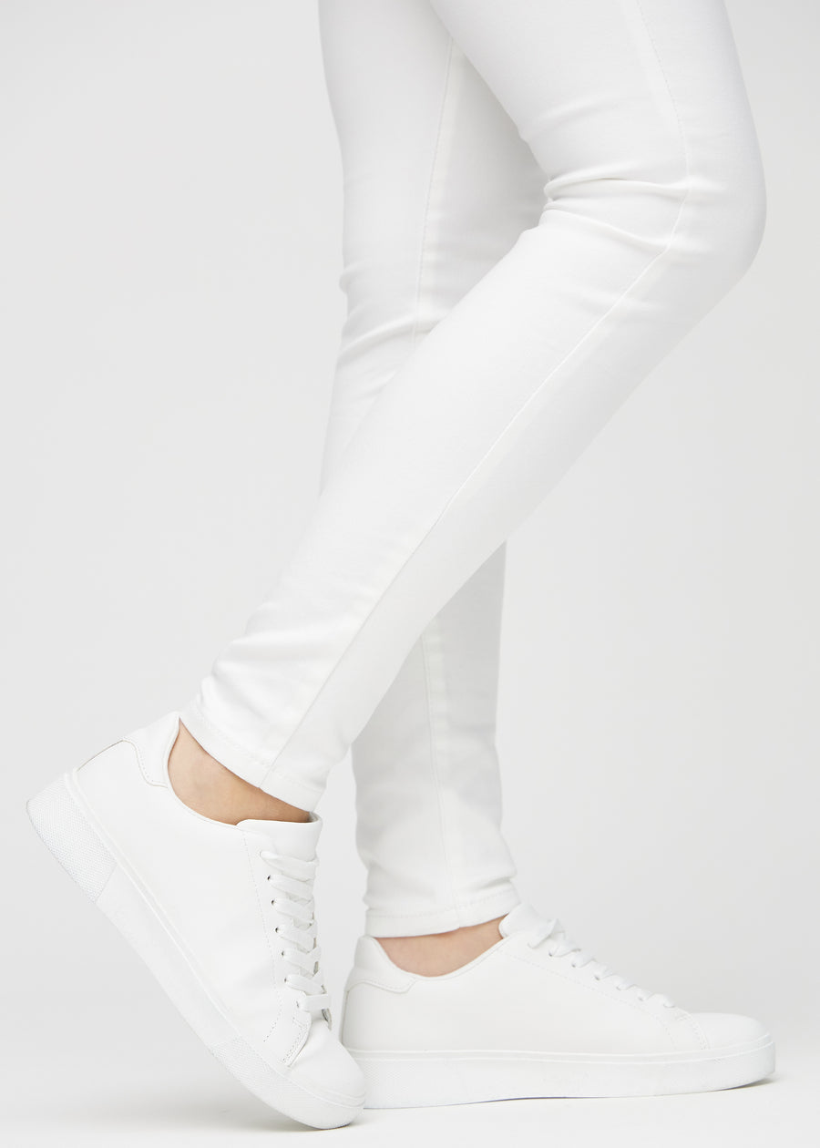 Skinny jeans for women in white, color Marguerites. Close-up of the snug-fitting leg openings at the ankles on a model.