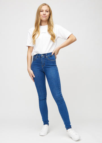 Skinny jeans for women in dark blue, color Oceans. Full-length view of a model in the jeans.