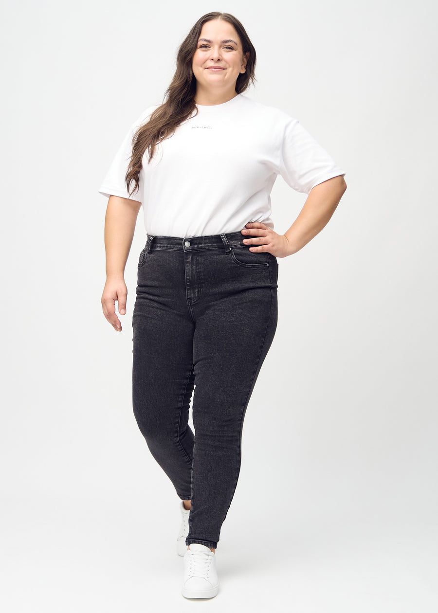 Full image of a plus-size model in dark grey denim skinny jeans.