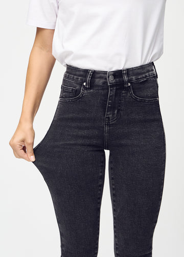 The model stretches the jeans at the thigh to show the stretch.