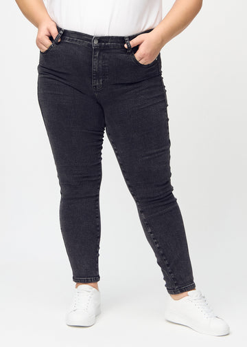 Dark grey denim skinny jeans, model name Shadows, which fits closely to the leg on a plus-size model, seen from the front.