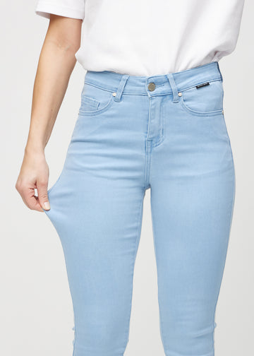 Skinny jeans for women in light blue, color Skies. A model stretches the jeans at the thigh to show the fabric&