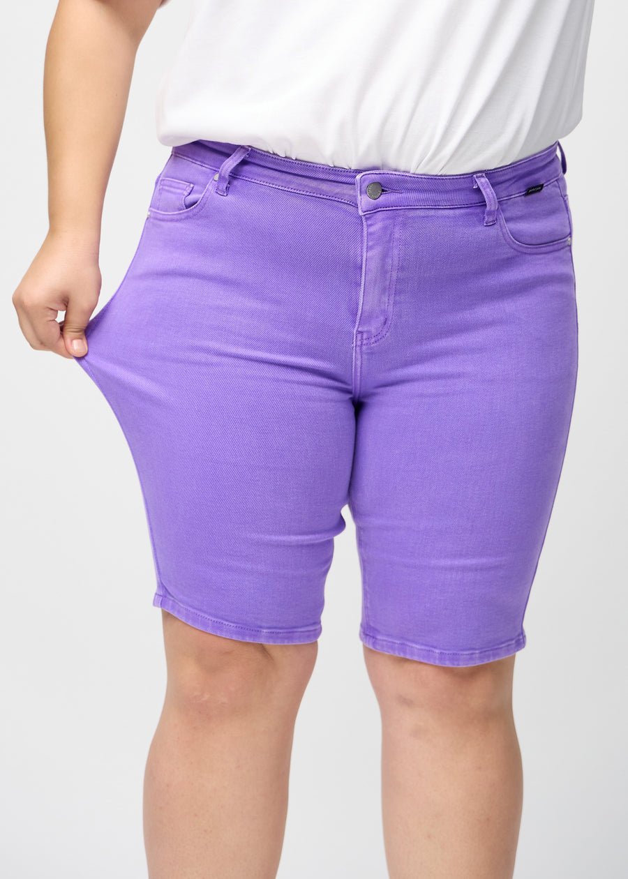 The plus-size model stretches the shorts at the thigh to show the stretch.