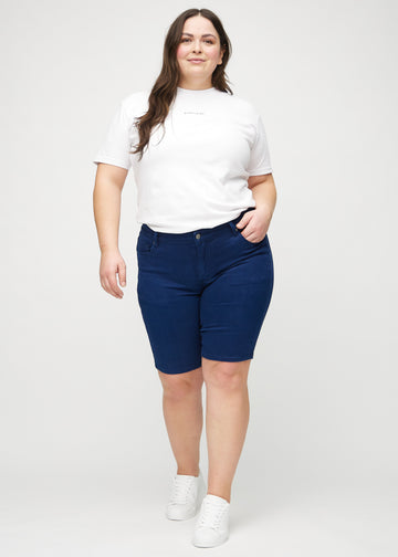 Full image of a plus-size model in dark blue skinny middle shorts.