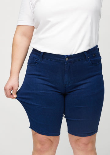 The plus-size model stretches the shorts at the thigh to show the stretch.