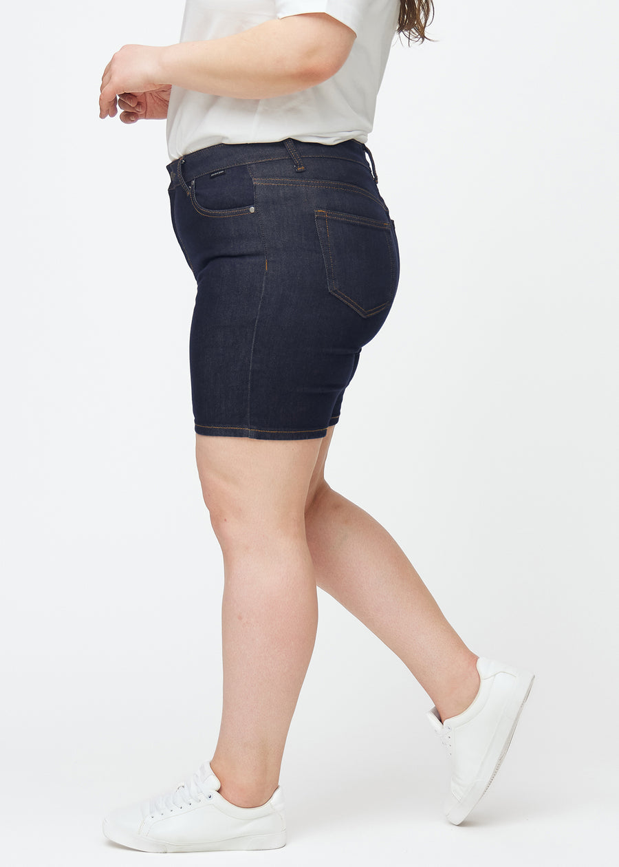 Deep dark blue denim shorts for women in the colour Midnights with a skinny fit seen from the side on a plus-size model.