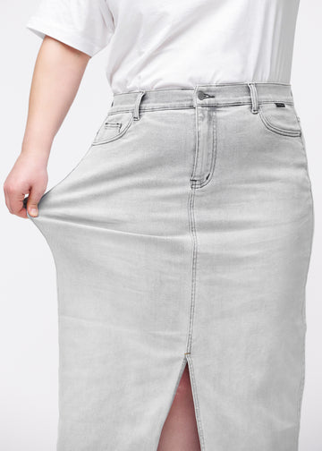 Long light grey denim skirt for women in the color Ashes. A plus-size model stretches the fabric at the hip to demonstrate its stretch.