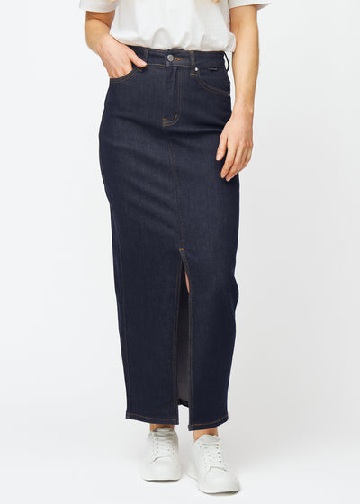Long deep dark blue denim skirt for women in the colour Midnights, sitting at the hips and falling straight to the ankles, with a front slit starting just below the knee, seen from the front.