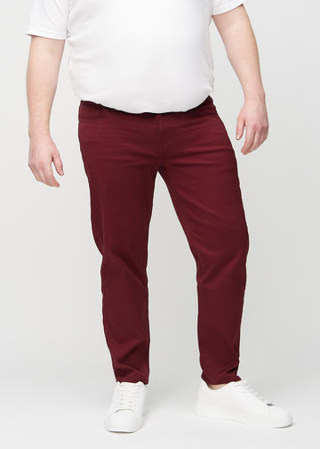 Dark red regular jeans, model name Santas, which goes straight down the leg on a plus-size model, seen from the front.