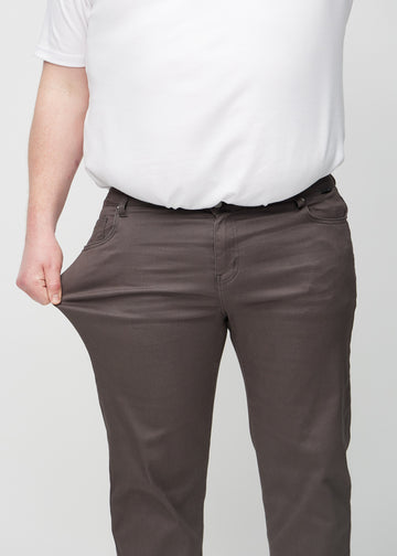 The plus-size model stretches the jeans at the thigh to show the stretch.