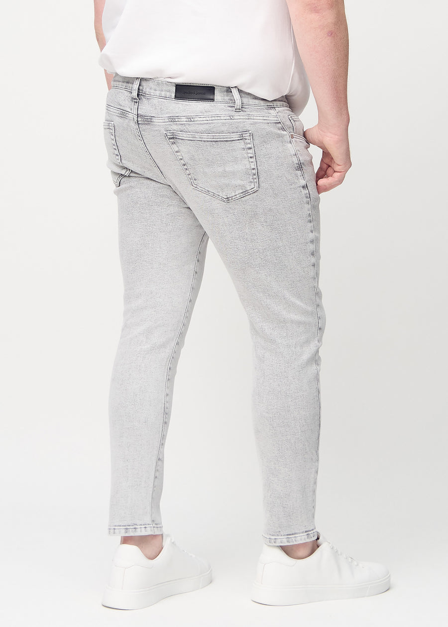 Light grey denim slim jeans viewed from the back on a plus-size model to show the full product.