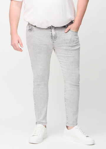 Light grey denim slim jeans, model name Ashes, fitted closely along the legs on a plus-size model, front view.