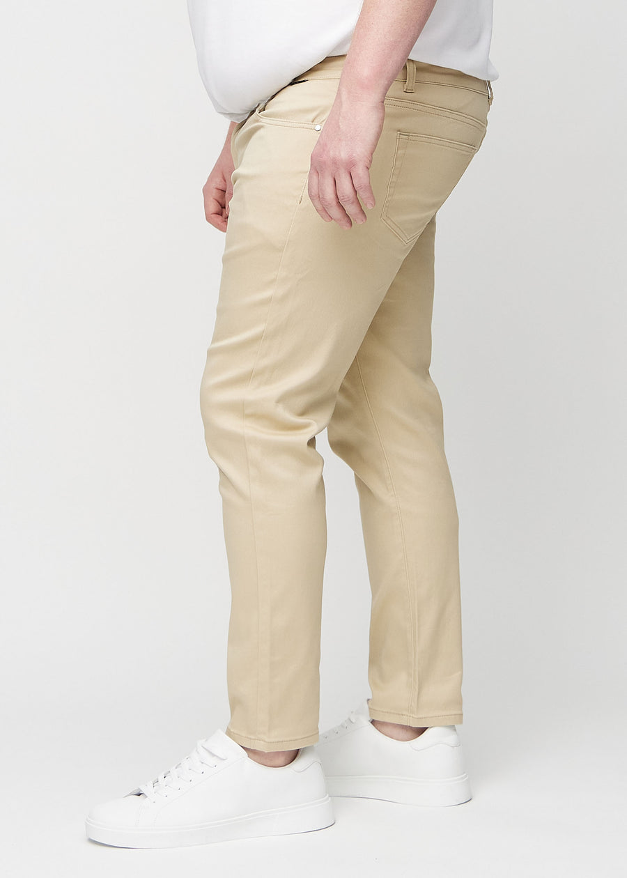 Beige slim jeans viewed from the side on a plus-size model.
