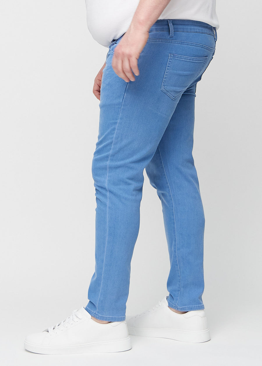 Blue slim jeans viewed from the side on a plus-size model.