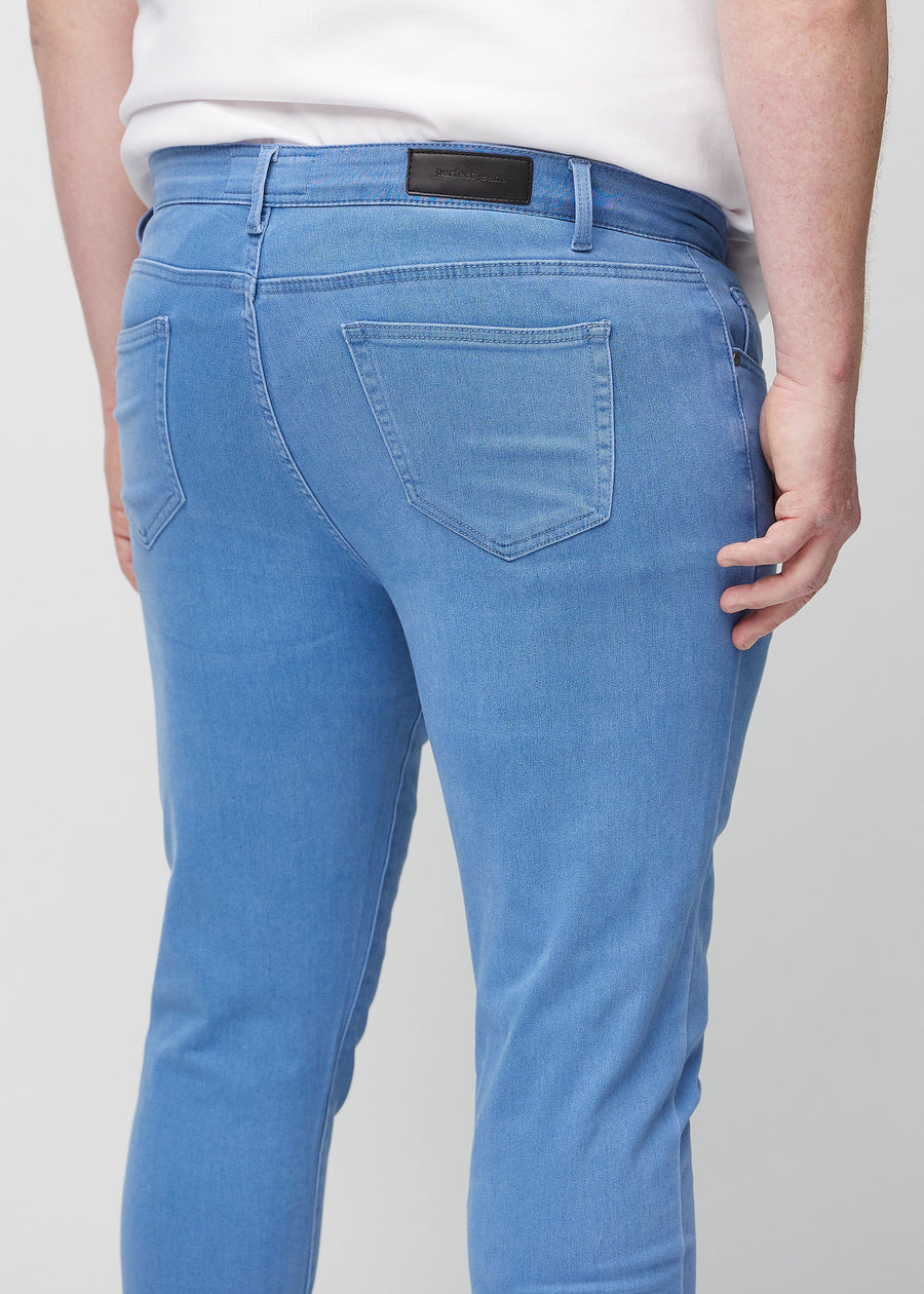 Close-up back view of blue slim jeans on a plus-size model showing details.